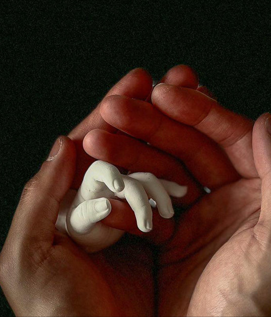 Hands holding a small white figurine against a dark background